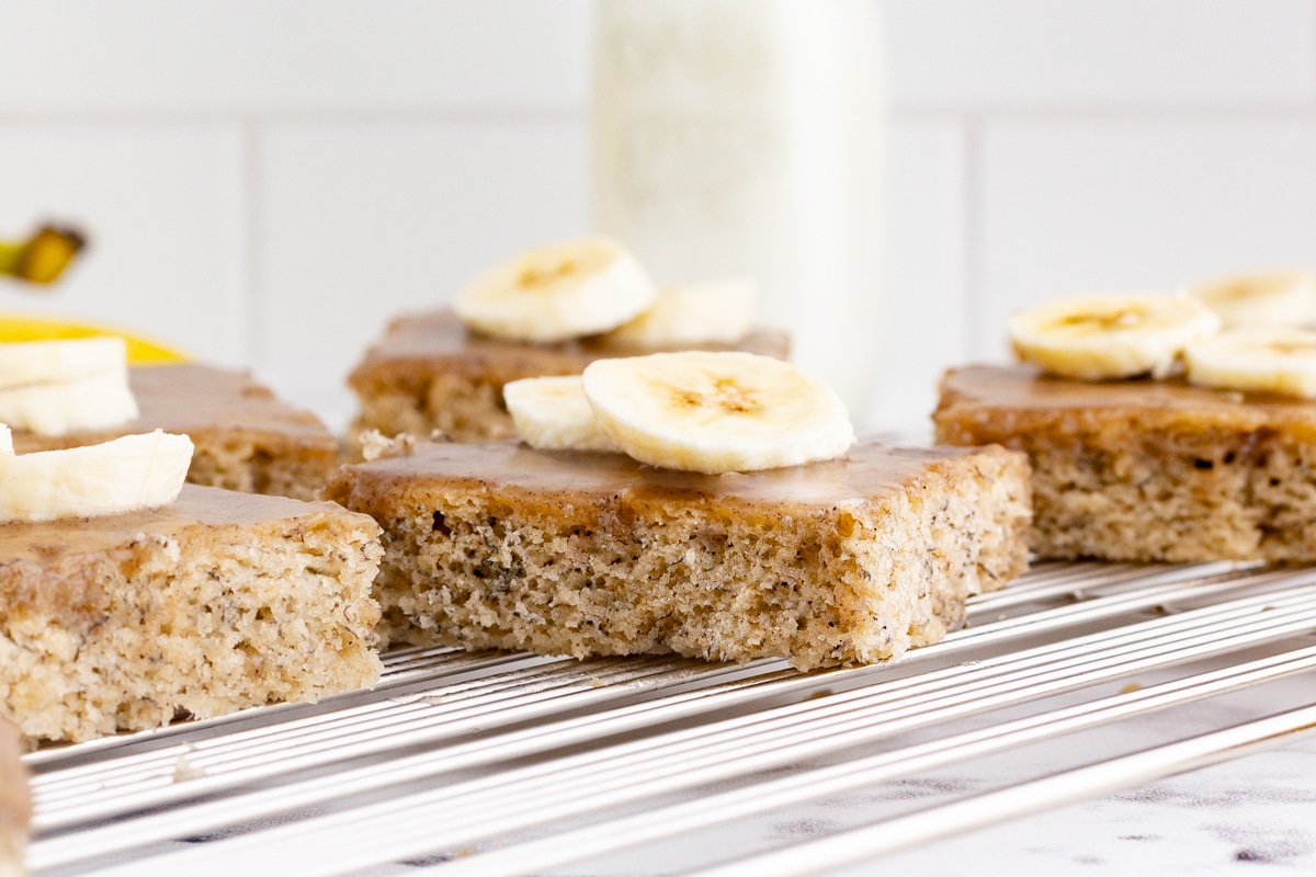 slices of banana cake topped with fresh banana slices on a cooling rack