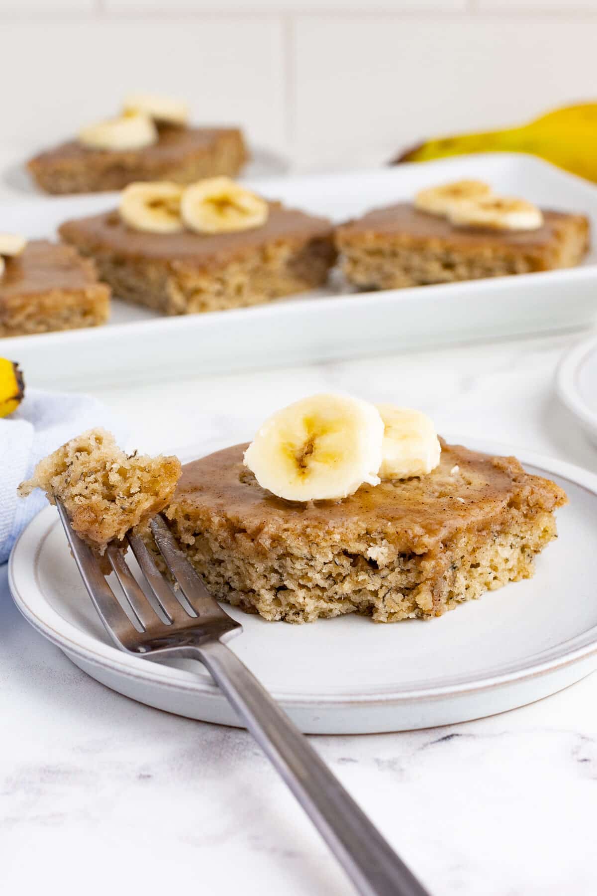 banana sheet cake with brown butter icing topped with fresh banana slices