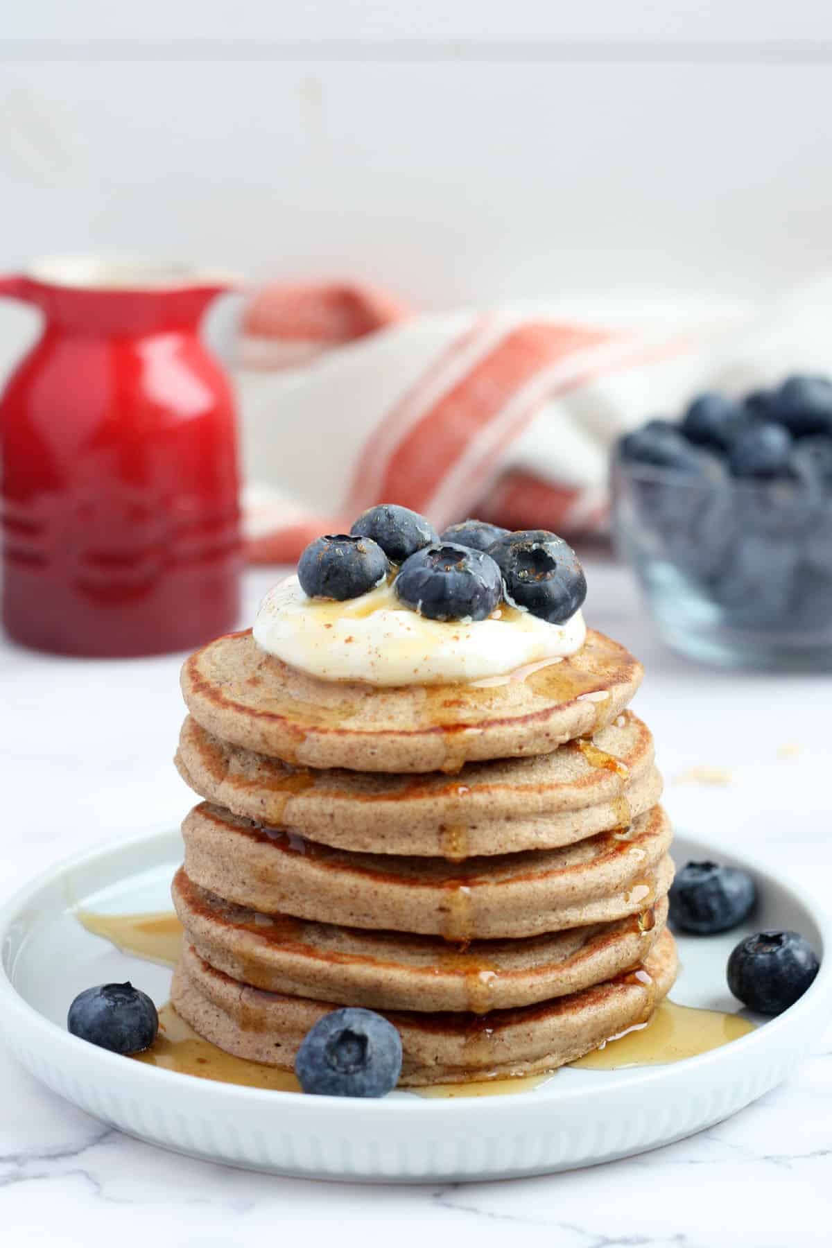 Stack of healthy pancakes topped with yogurt and fresh blueberries