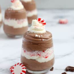 Garnish chocolate and peppermint mousse in a clear glass with whipped cream and mints