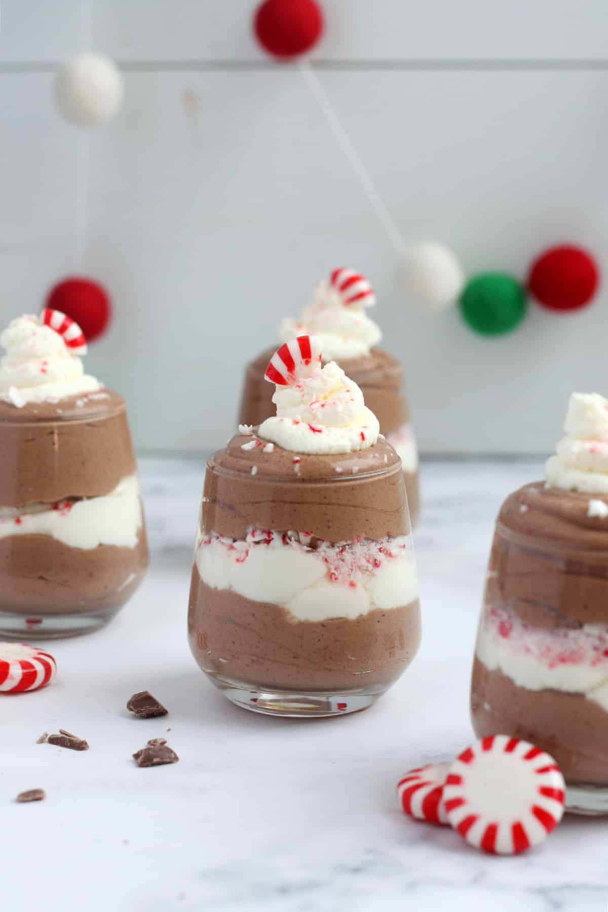 small glasses filled with peppermint mousse and whipped cream, topped with crushed peppermint