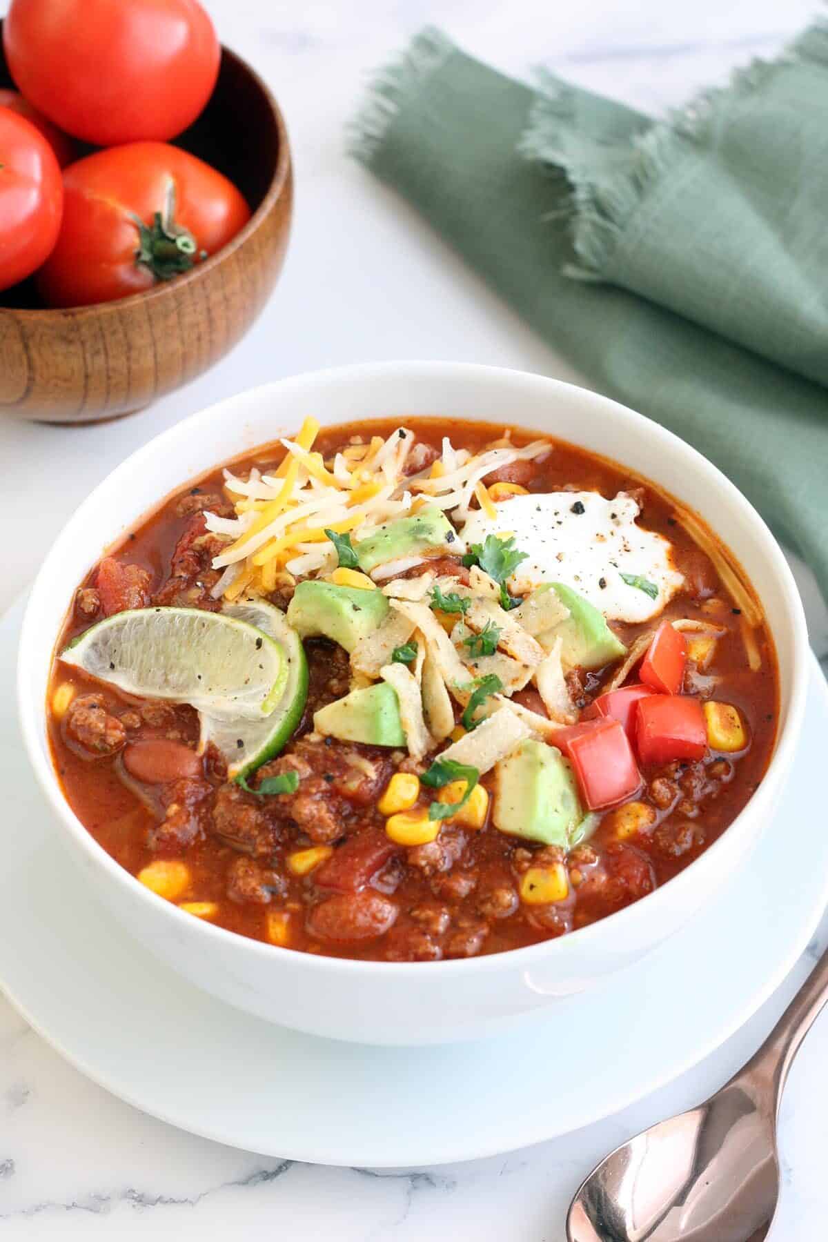 Taco soup in a white bowl topped with avocado cheese and lime slices