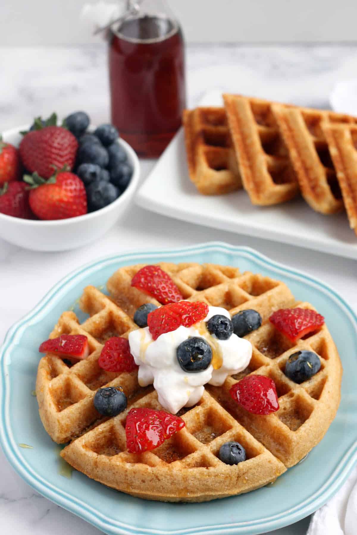 whole wheat waffles topped with whipped cream, fresh fruit and maple syrup