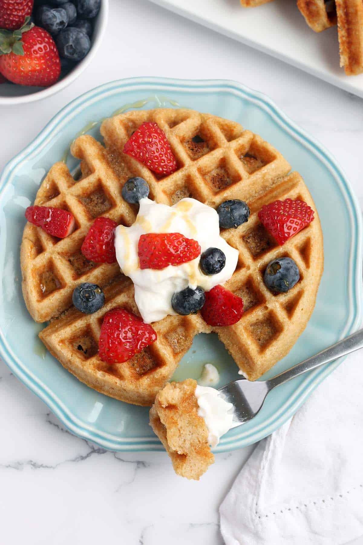 overhead shot of a whole wheat waffle topped with berries and syrup