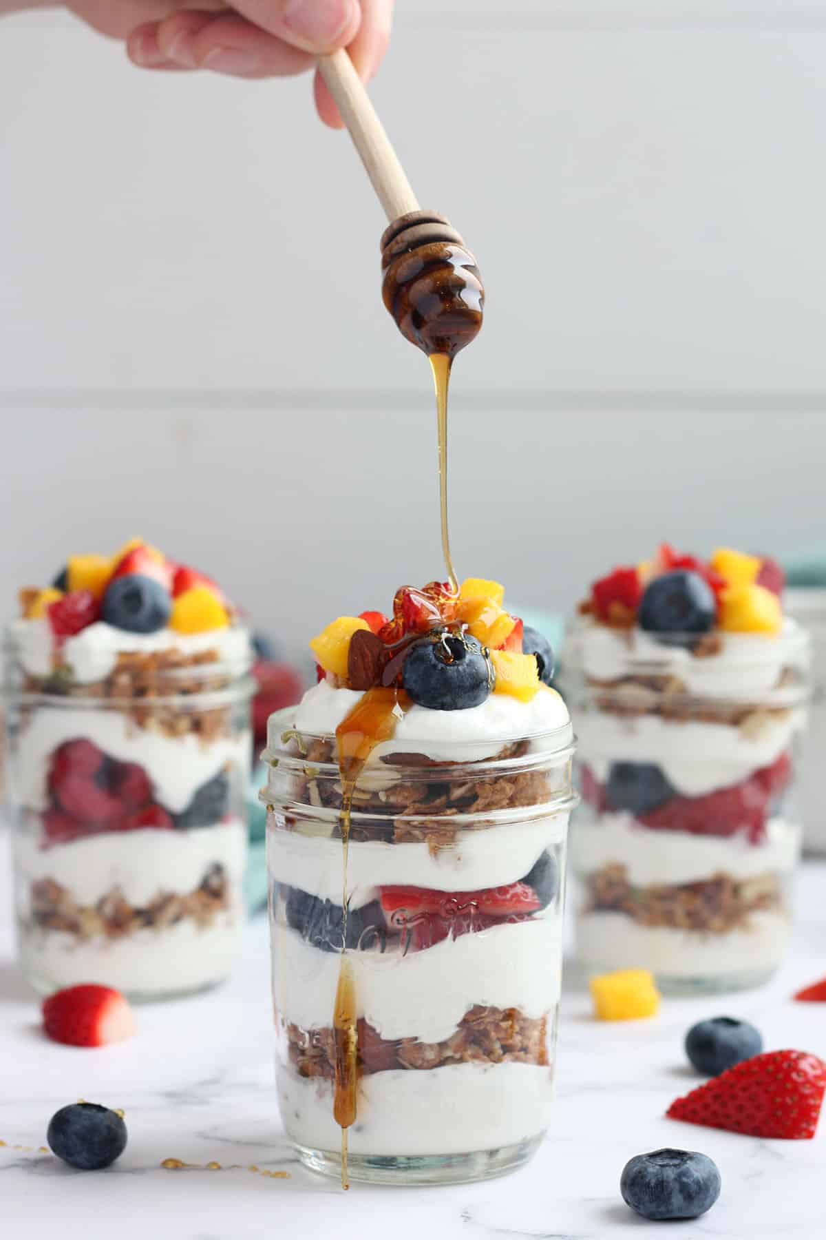 a yogurt parfait in a glass jar drizzled with honey