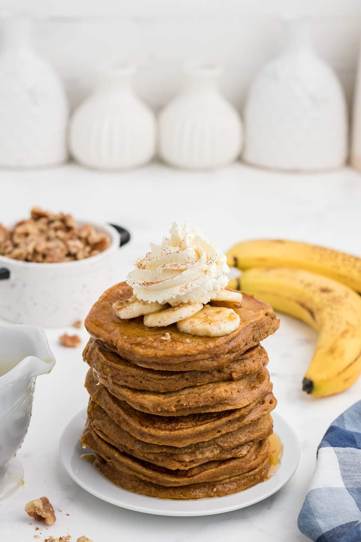 a stack of sweet potato pancakes topped with bananas and whipped cream