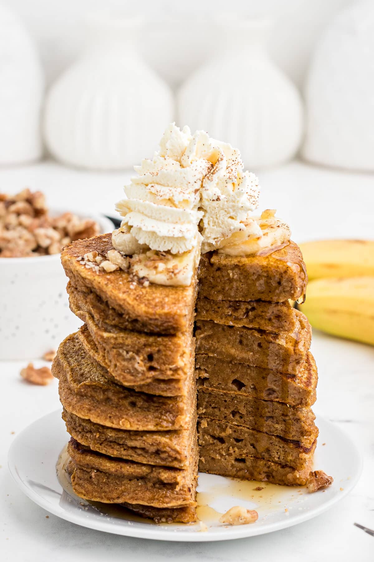 a stack of sweet potato pancakes with a slice taken out and drizzled with maple syrup