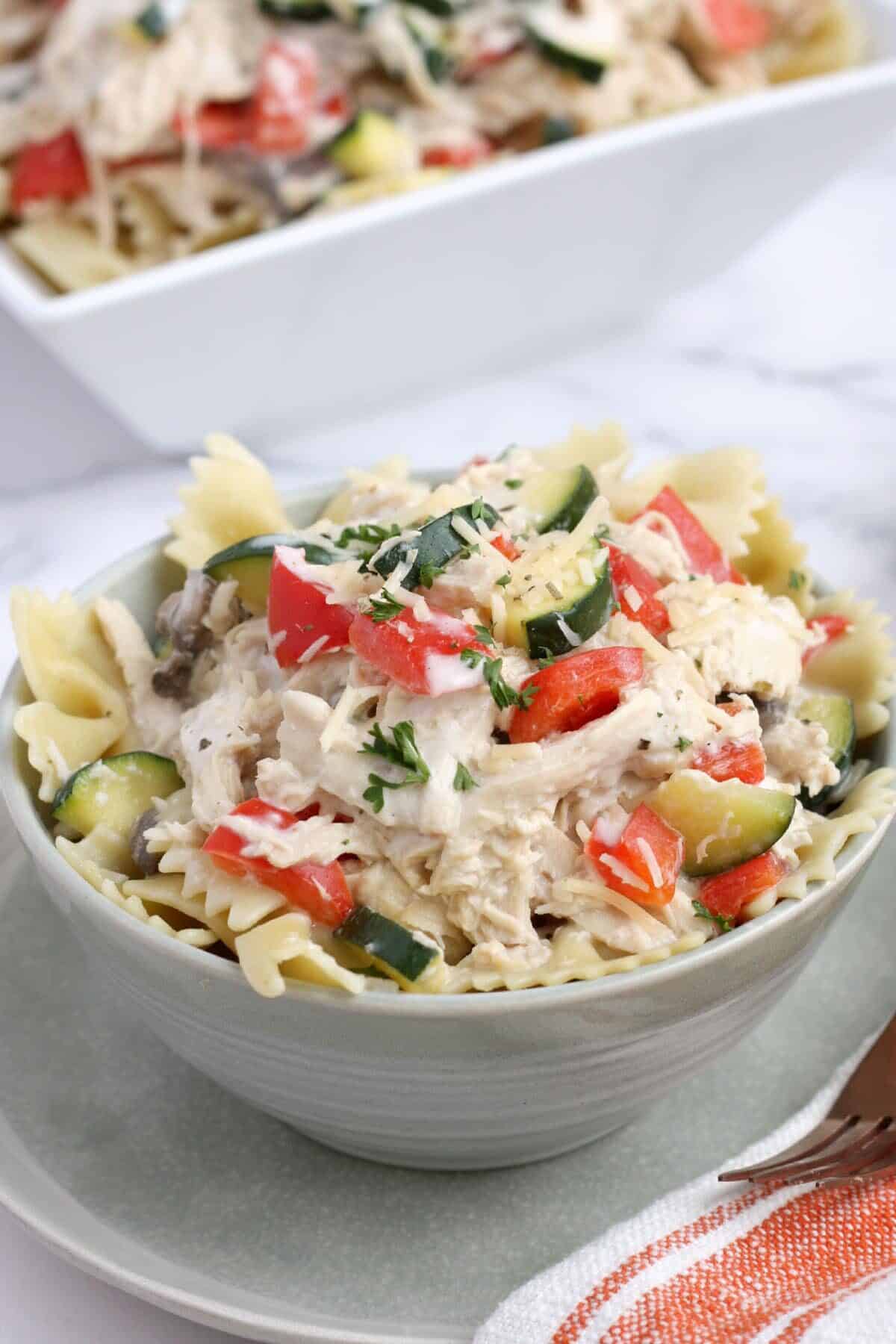 A bowl of crockpot italian chicken with zucchini and peppers served over pasta