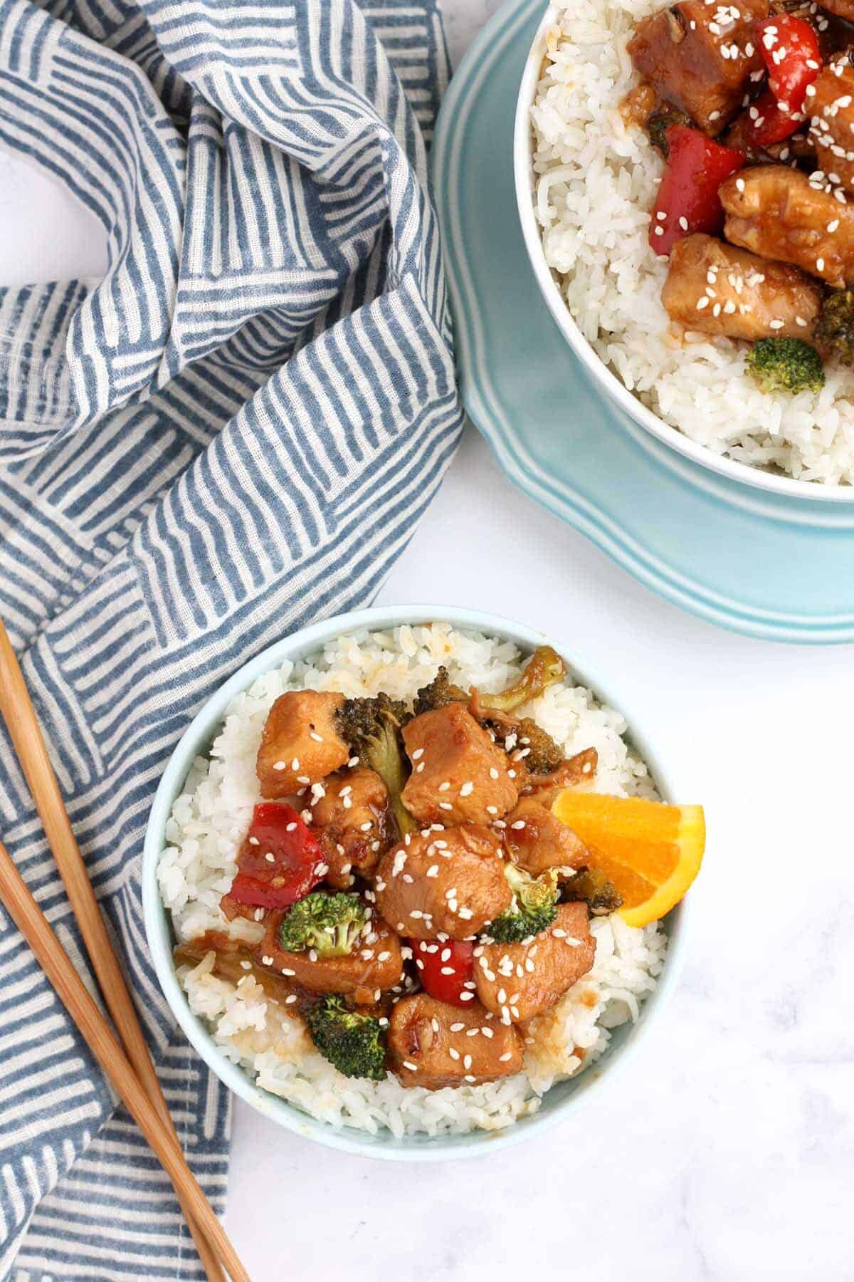 overhead shot of orange chicken topped with sesame seeds with chopsticks