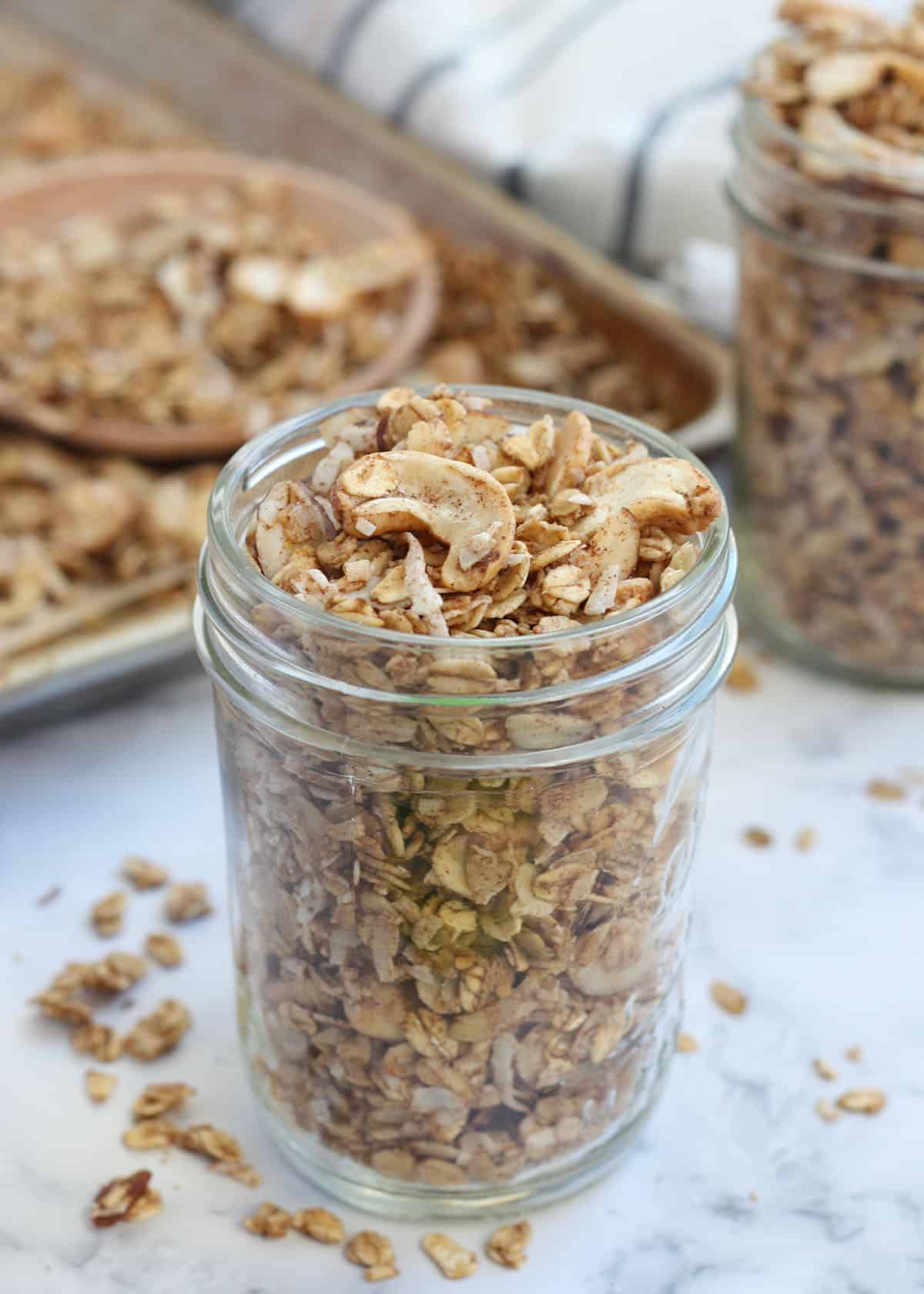 sugar free granola in a small mason jar with a baking sheet with granola in the background