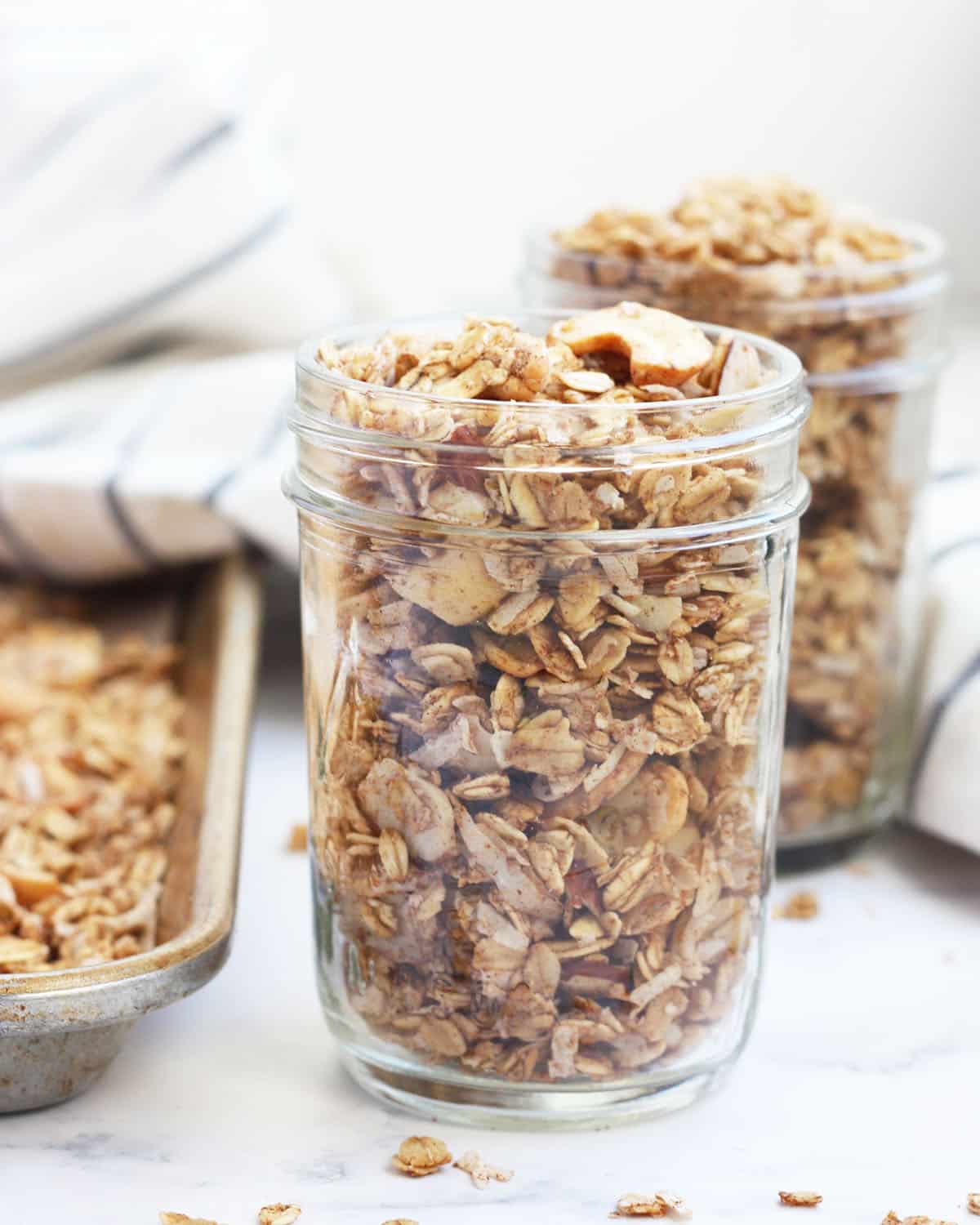 sugar free granola in a small mason jar with a baking sheet in the background with granola on it