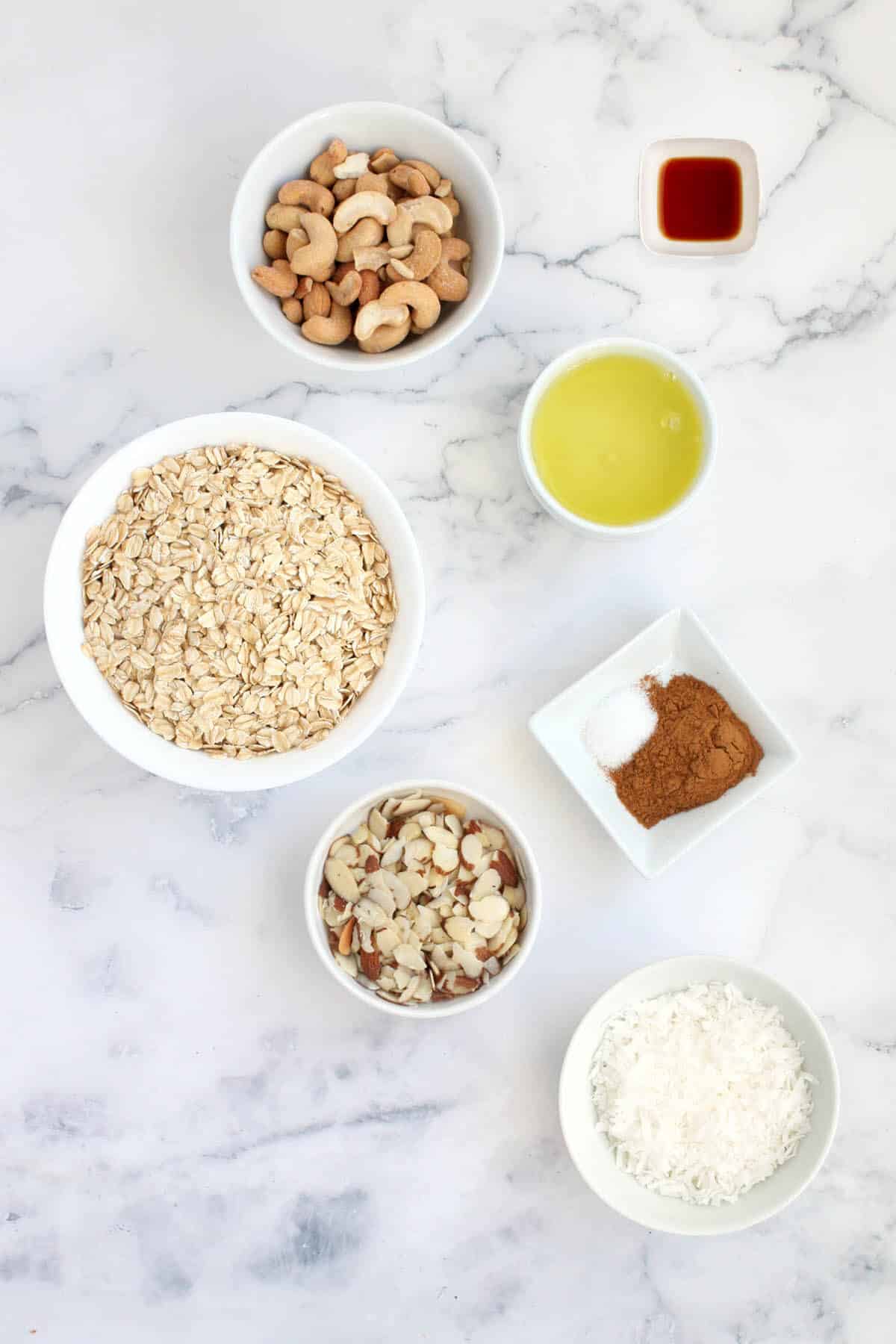 ingredients for sugar free granola: rolled oats, cashews, egg whites, sliced almonds, coconut flakes, cinnamon, salt, vanilla, coconut oil