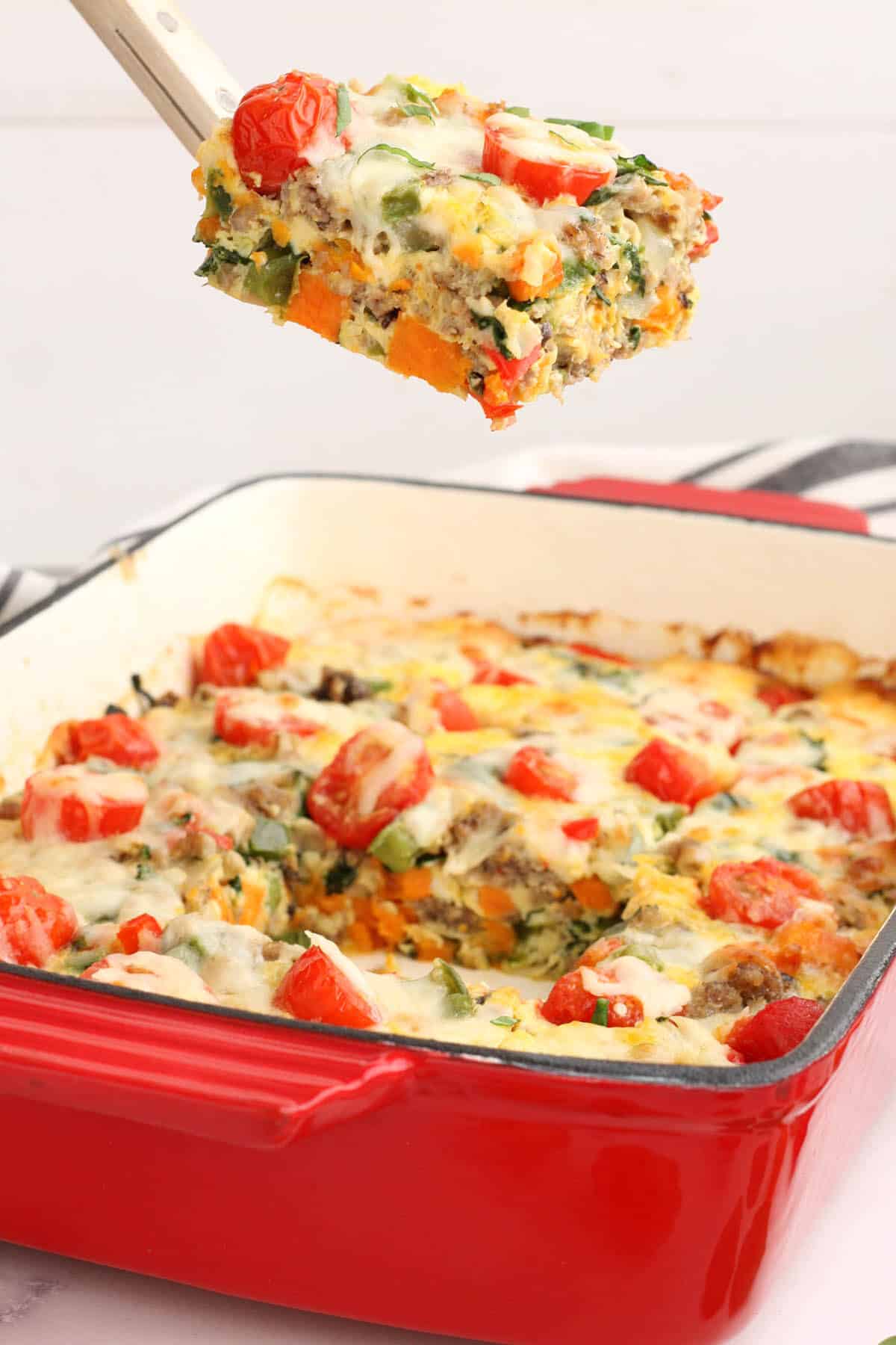 a square of sweet potato breakfast casserole being lifted out of the baking dish