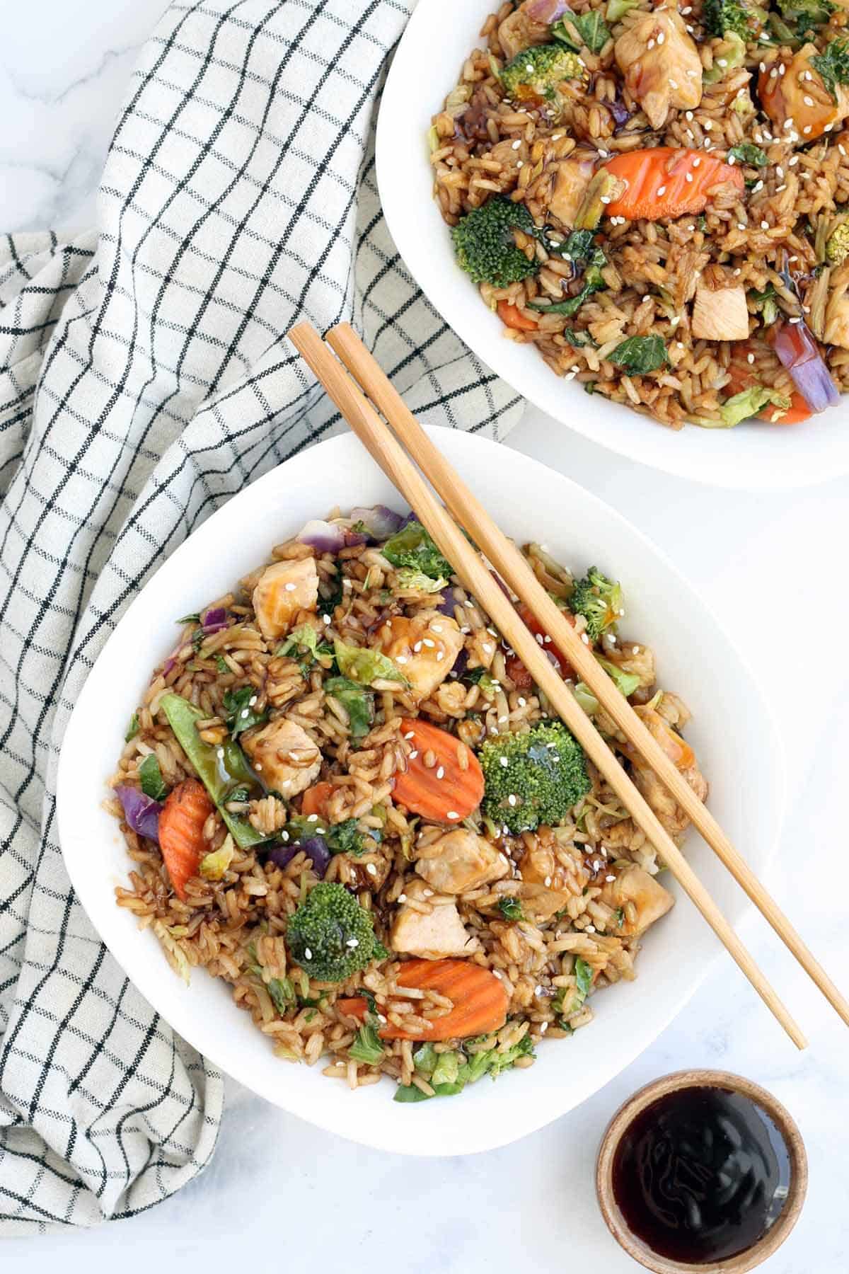 teriyaki chicken bowls with chopsticks and a bowl of teriyaki sauce