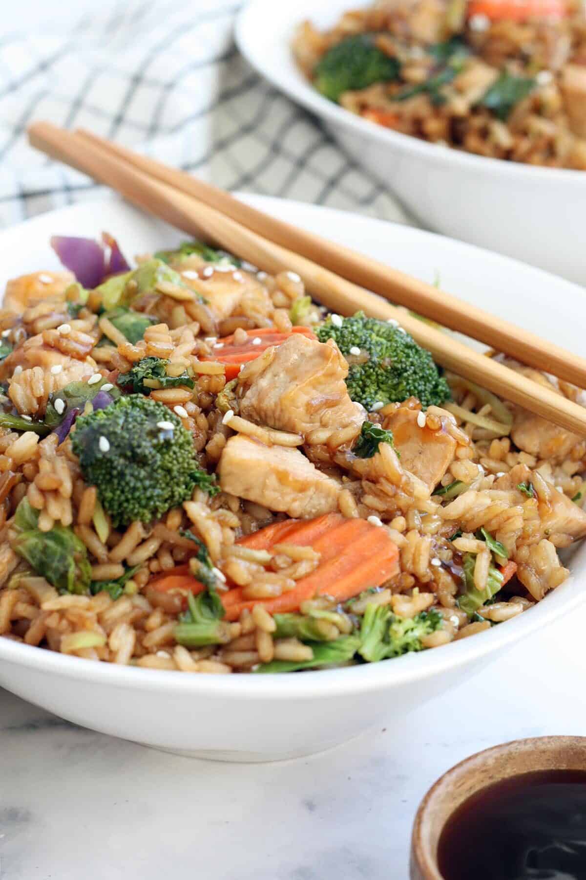 a close up of a teriyaki chicken bowl topped with sesame seeds