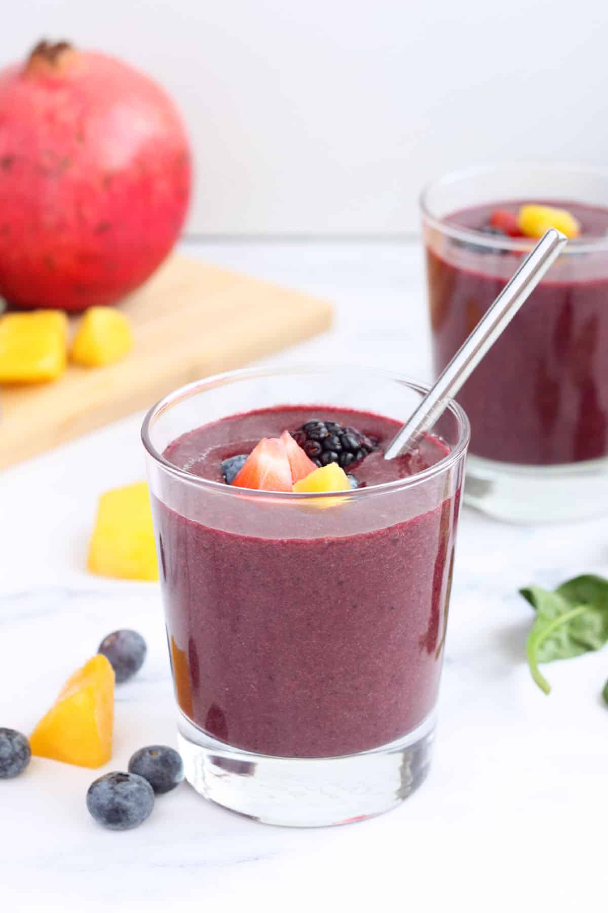 immune boosting shake in a glass with a metal straw topped with fruit