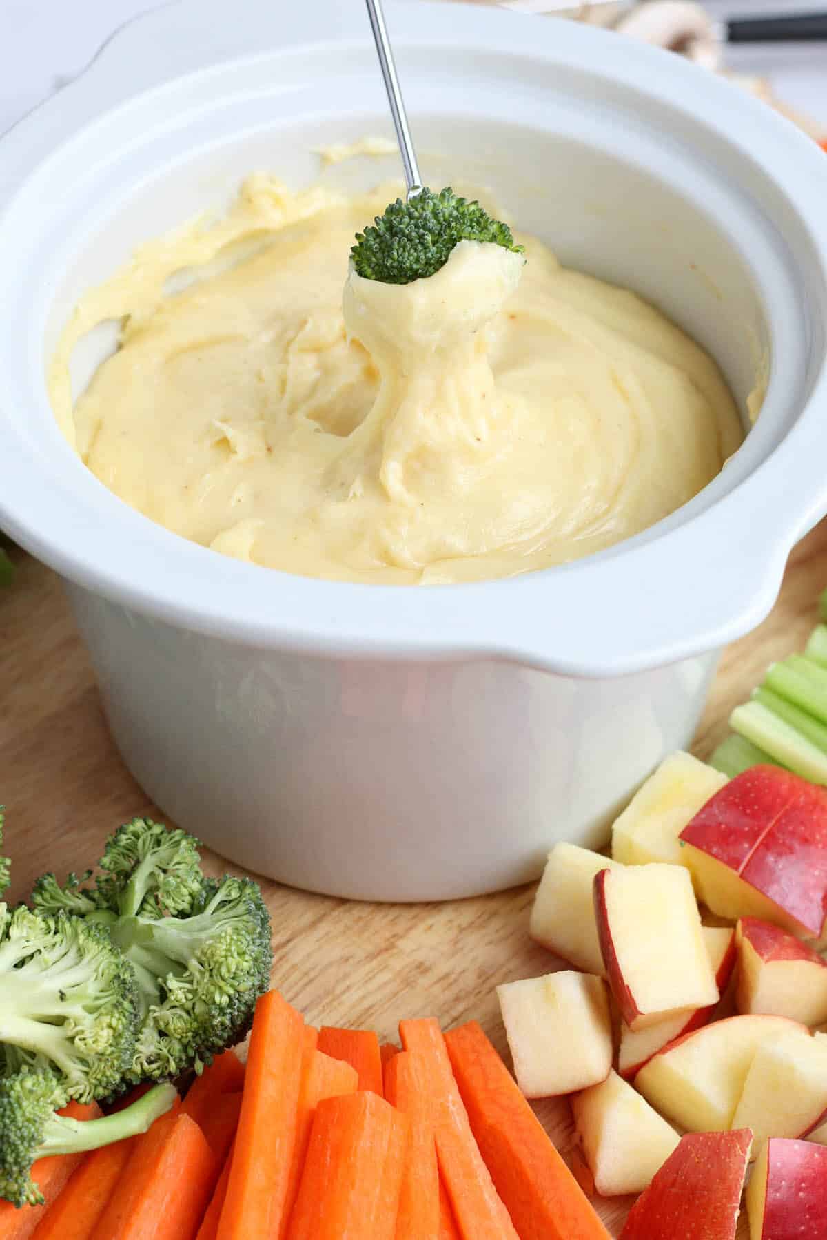 a broccoli floret being dipped into cheese fondue