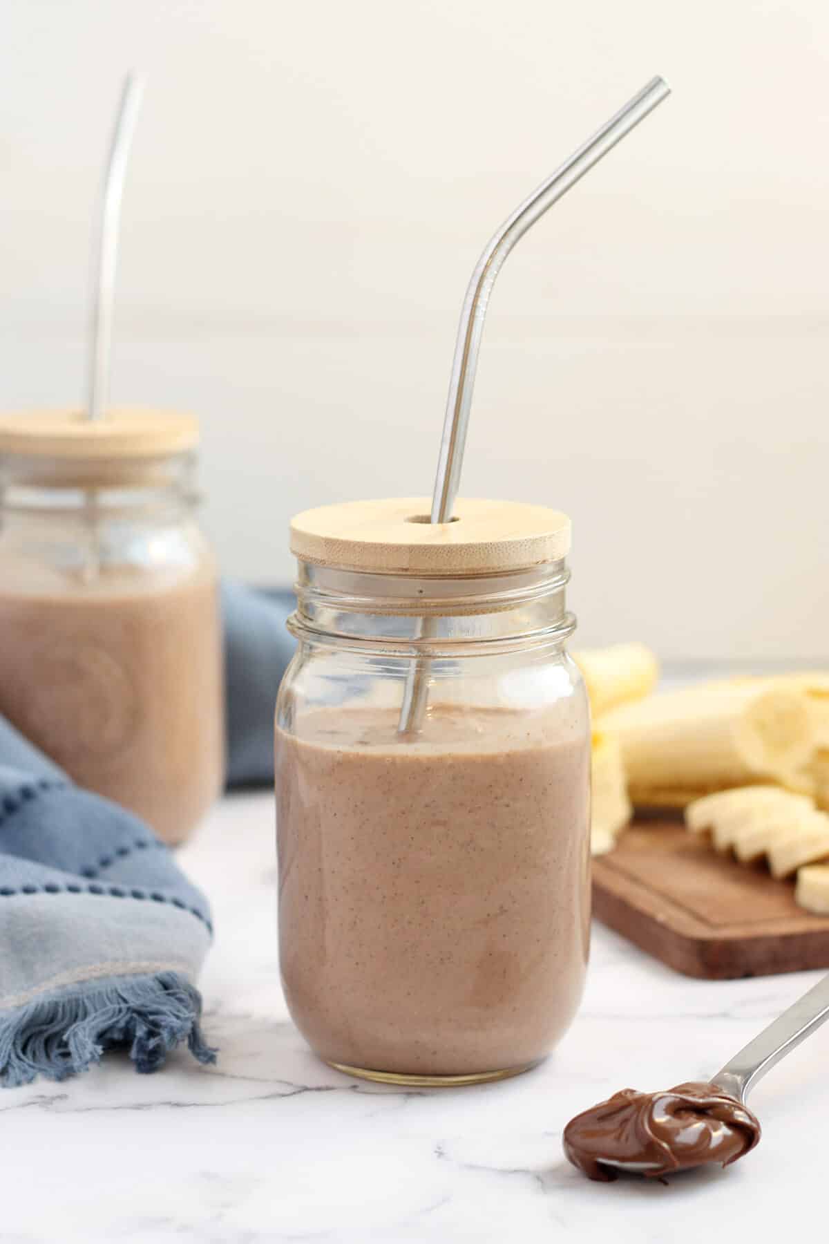 chocolate protein shake in a mason jar with a wooden lid and a metal straw