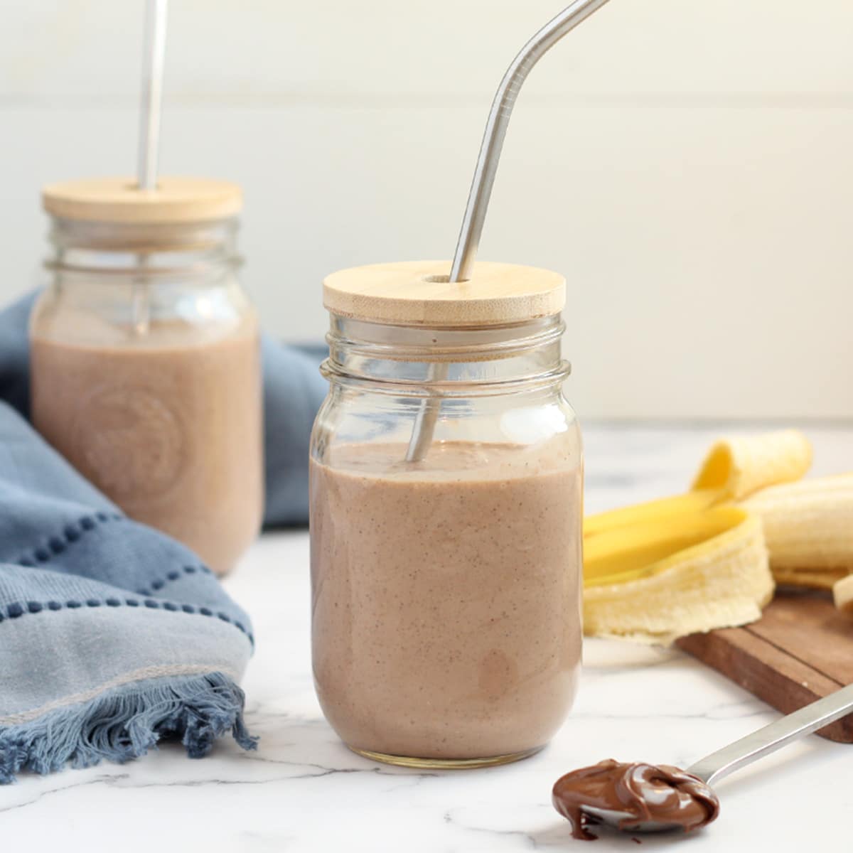 2 cups chocolate protein shake with banana background