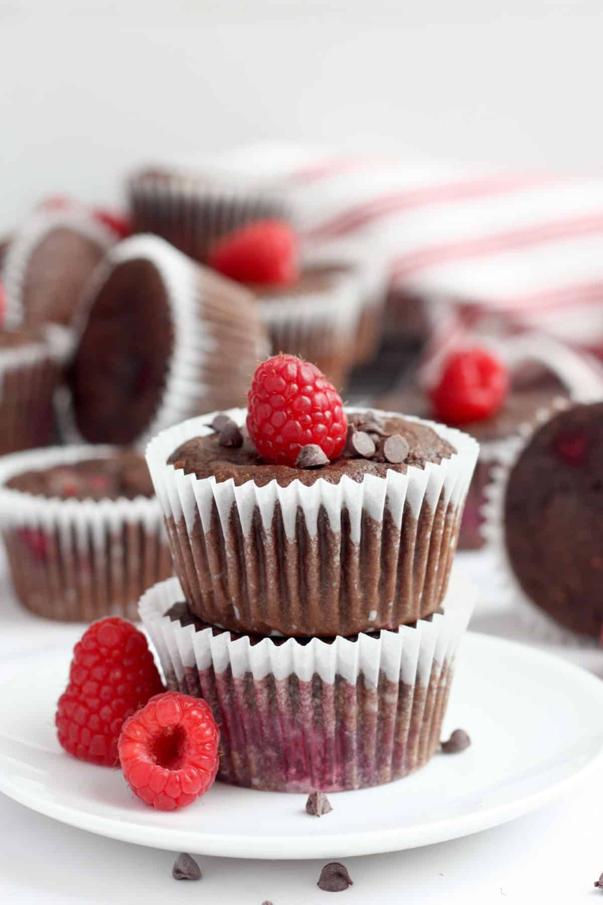 chocolate raspberry muffins in white liners topped with a fresh raspberry