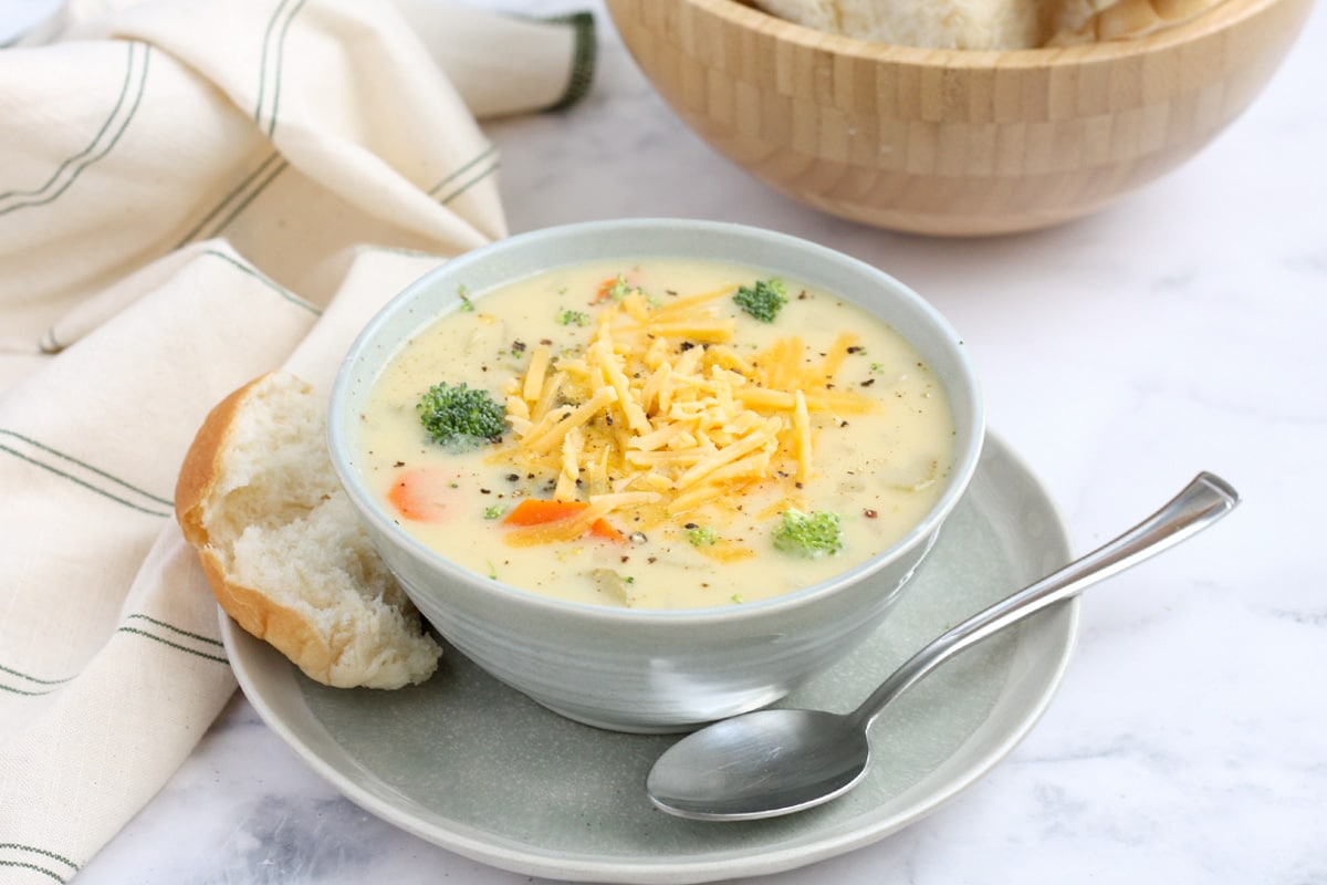 a bowl of crockpot vegetable soup served with a fresh roll