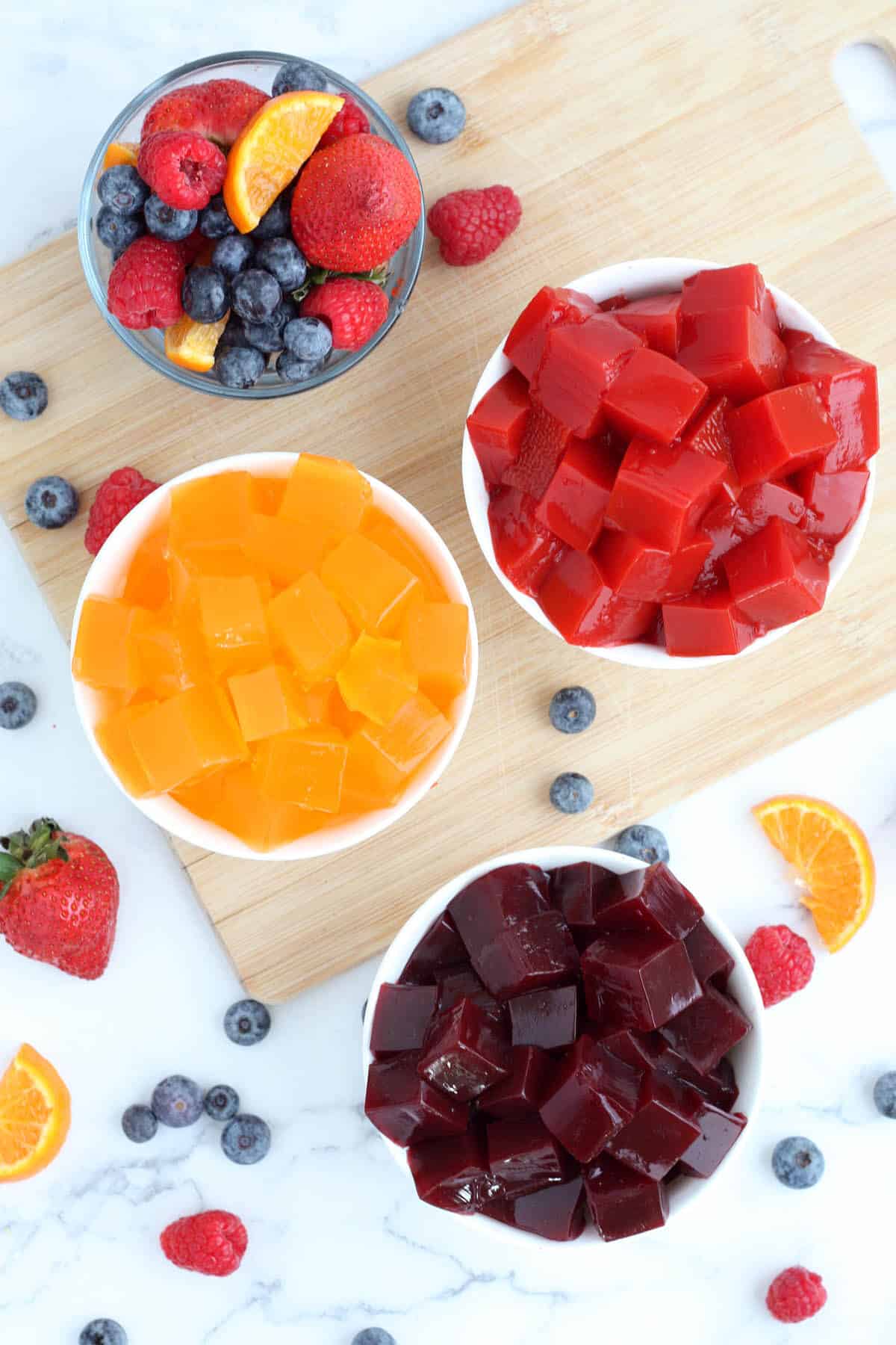 bowls of homemade jelly on a wooden board with fresh fruit