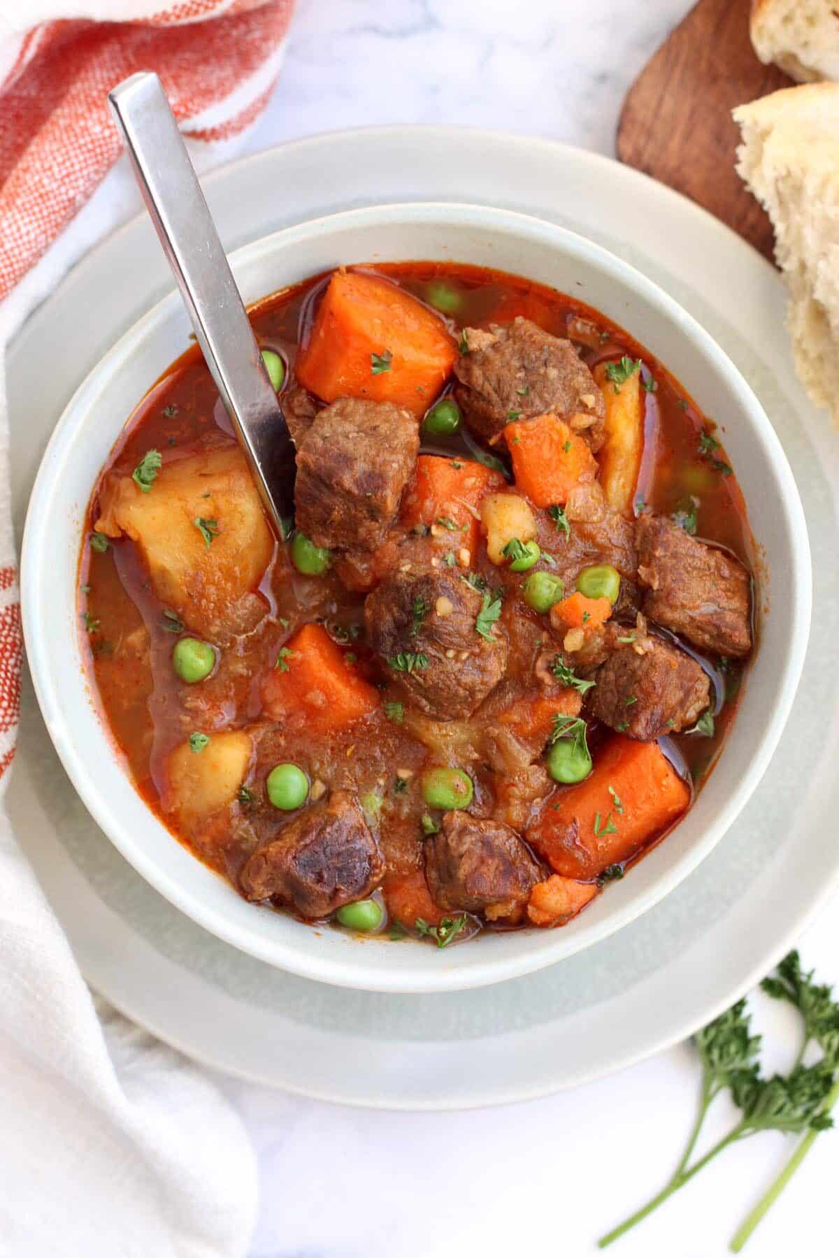 overhead view of a bowl of beef stew with a spoon in the bowl