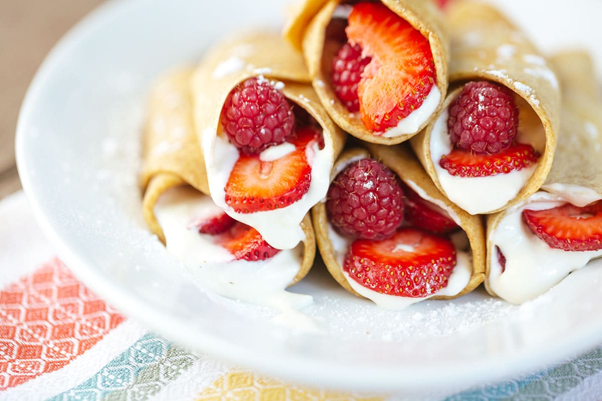 Close-up shot of strawberry crepes stacked on a white plate