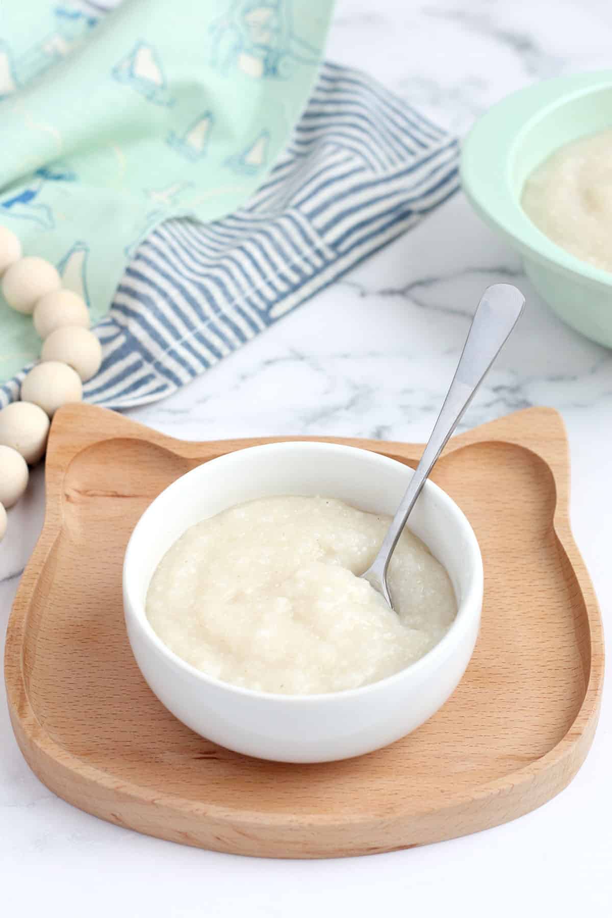 homemade baby cereal in a small white bowl with a spoon