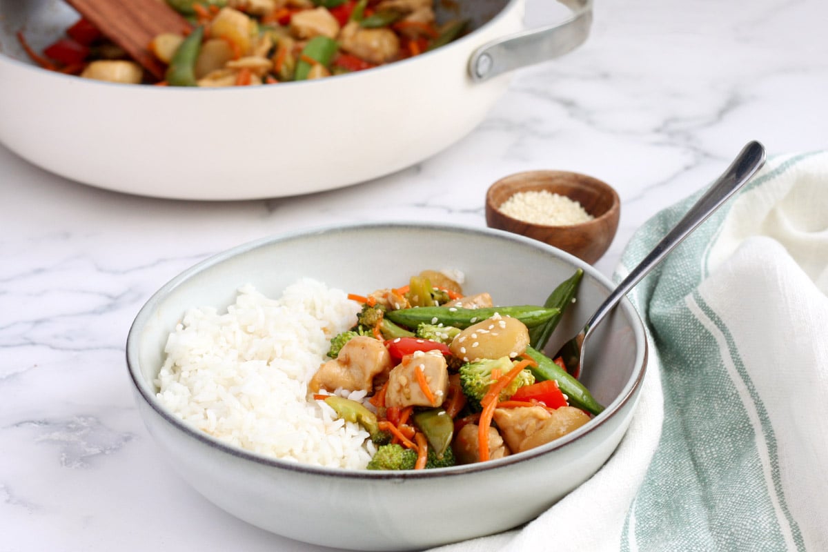 bowl of stir fry chicken with a green striped towel