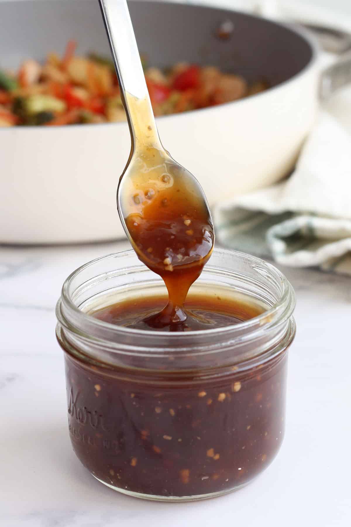 Homemade stir-fry sauce in a glass jar with a spoon