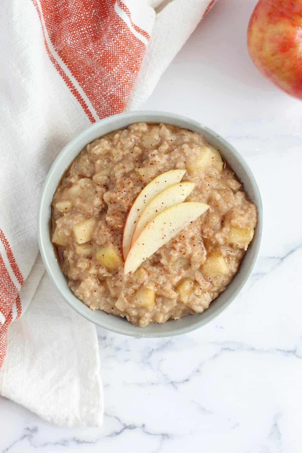 a bowl of apple oatmeal with fresh apples and cinnamon