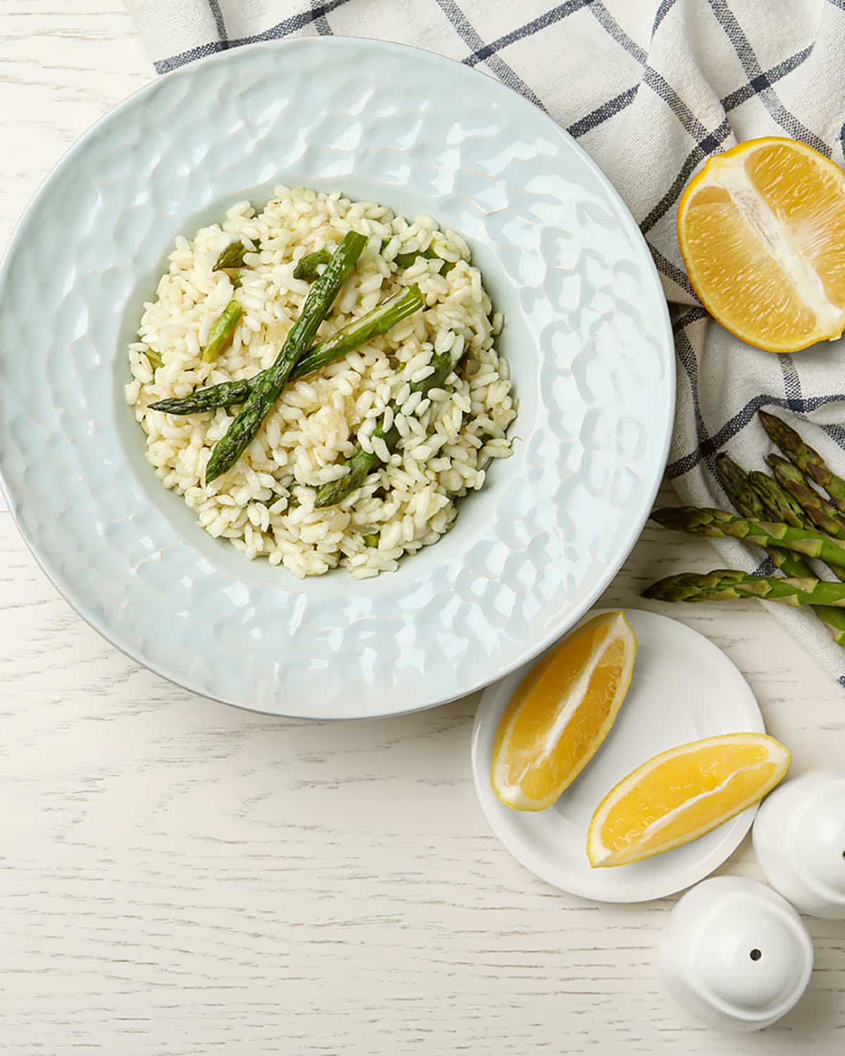 Delicious risotto with asparagus on white wooden table, flat lay.