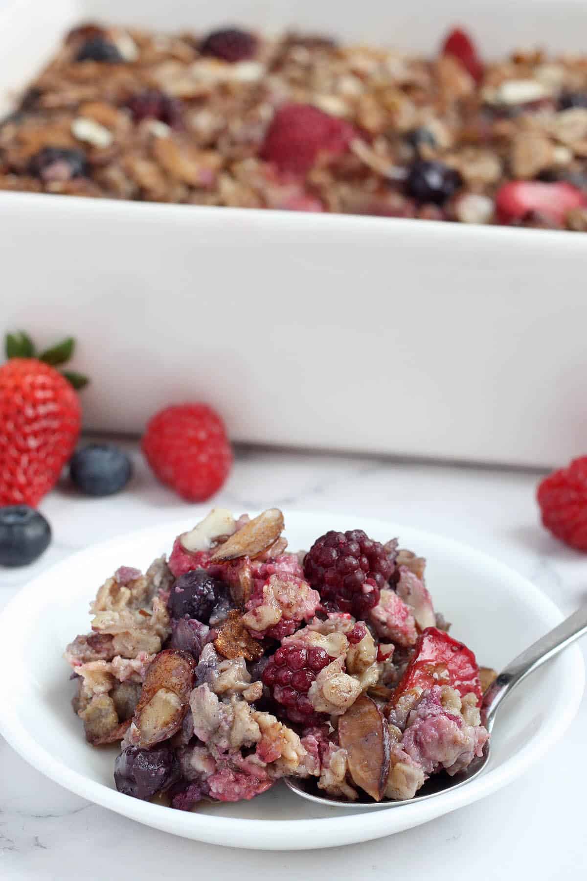 a serving of baked oatmeal with berries on a white plate with a spoon