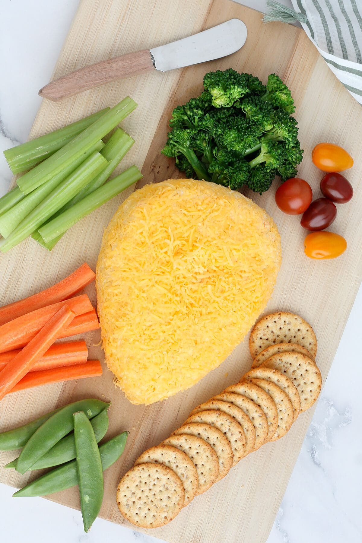 a cheeseball shaped like a carrot with crackers and vegetables