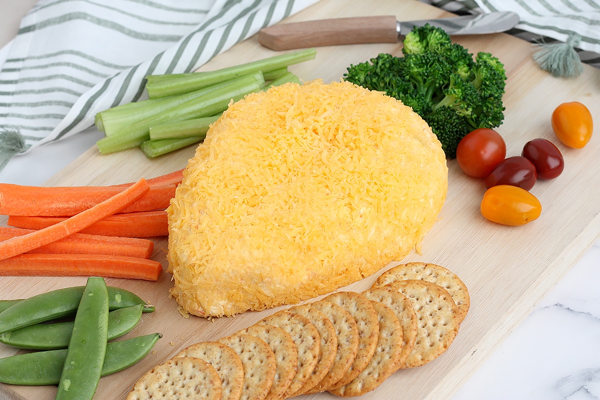 a cheeseball shaped like a carrot with crackers and vegetables