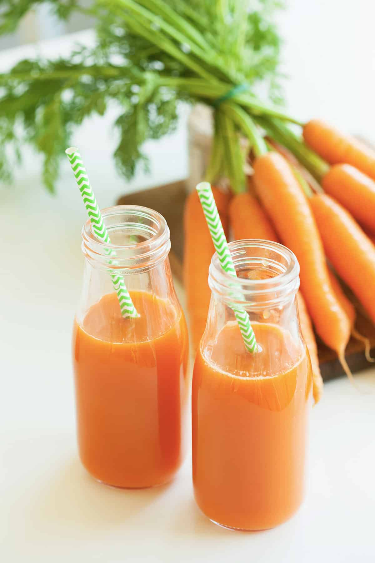 fresh carrot juice with carrots in the background