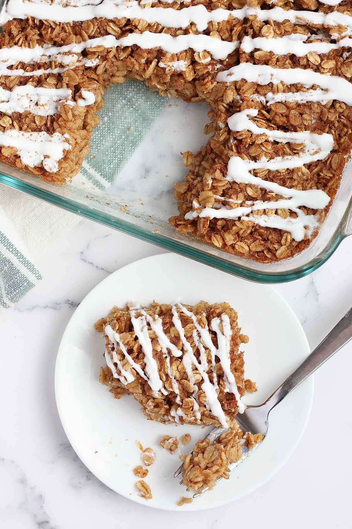 baked cinnamon roll oatmeal on a serving plate with a yogurt drizzle