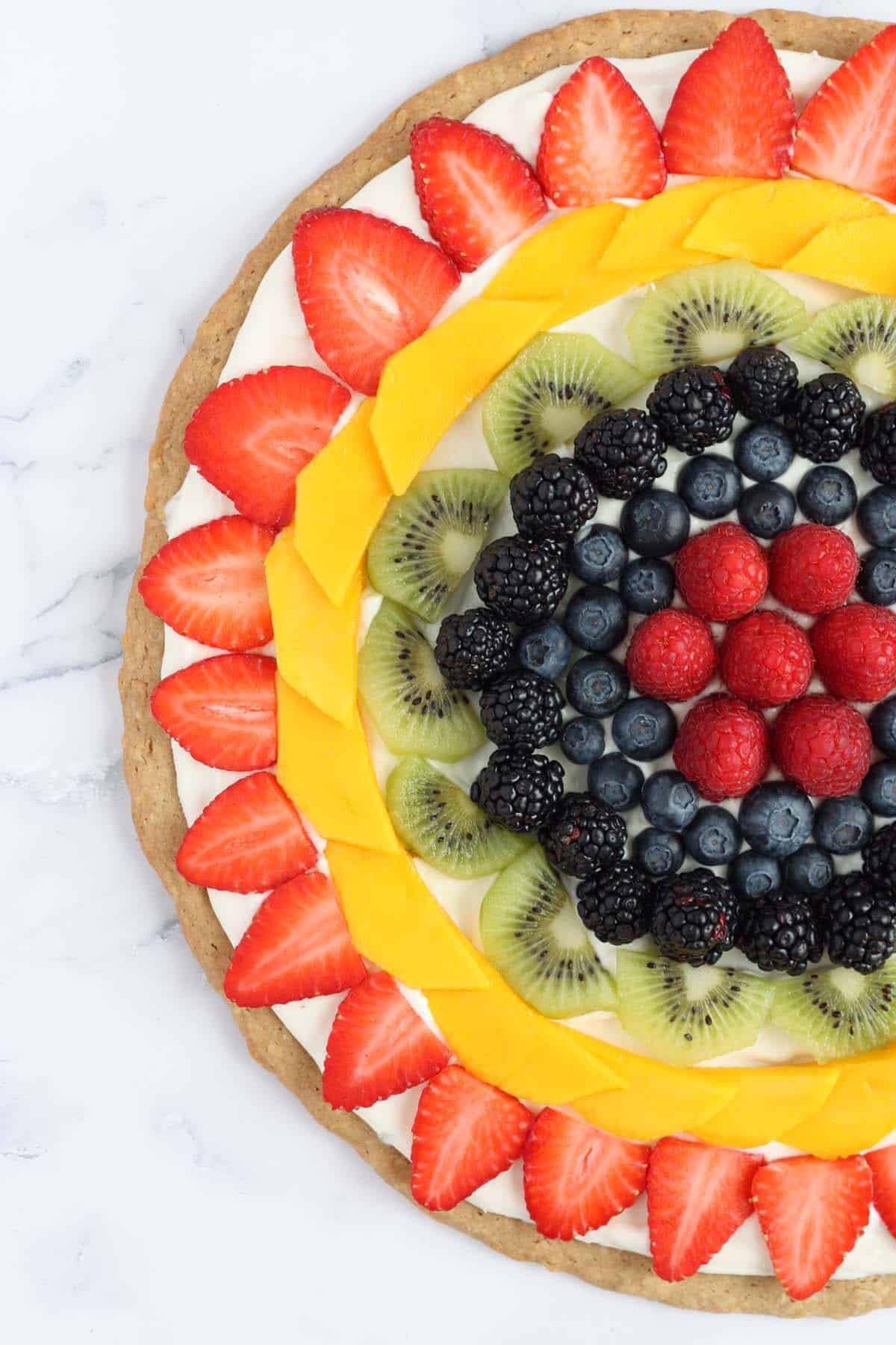 fruit pizza topped with fresh berries, kiwi and mango