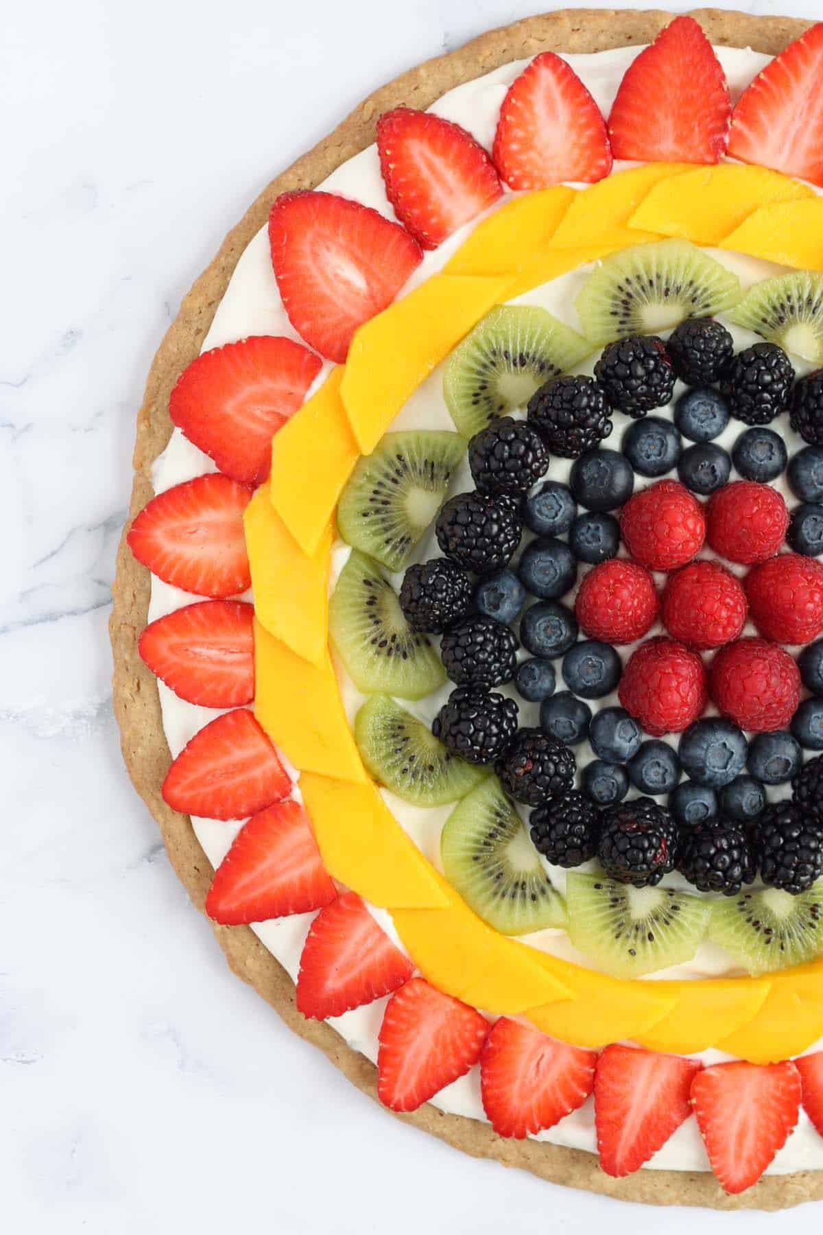 Fruit pizza topped with fresh berries, kiwi and mango