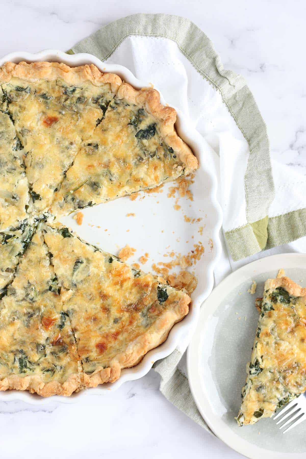 a spinach quiche in a white pie plate