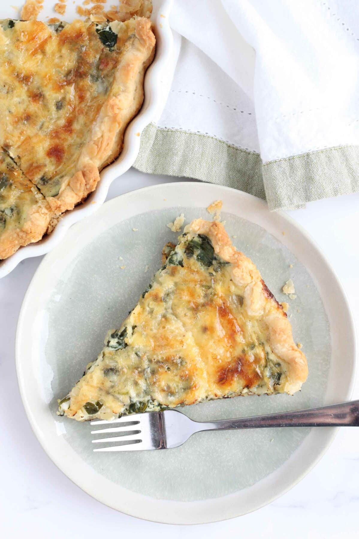 an overhead shot of spinach quiche on a blue plate