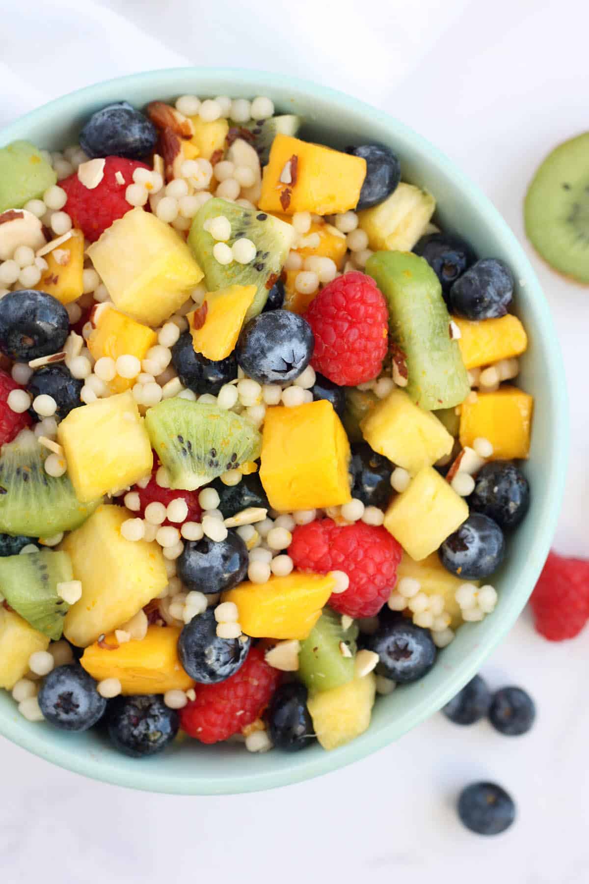 a bowl of fruit salad with couscous and slivers of almonds