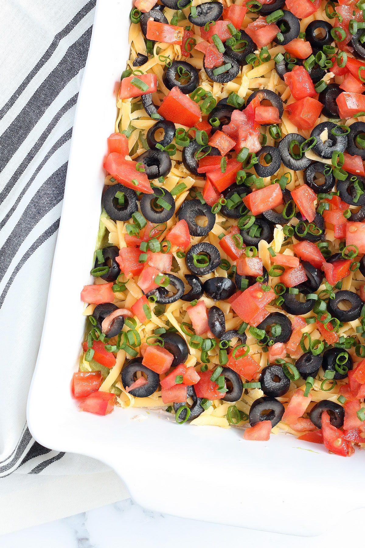 seven layer dip in a white ceramic dish