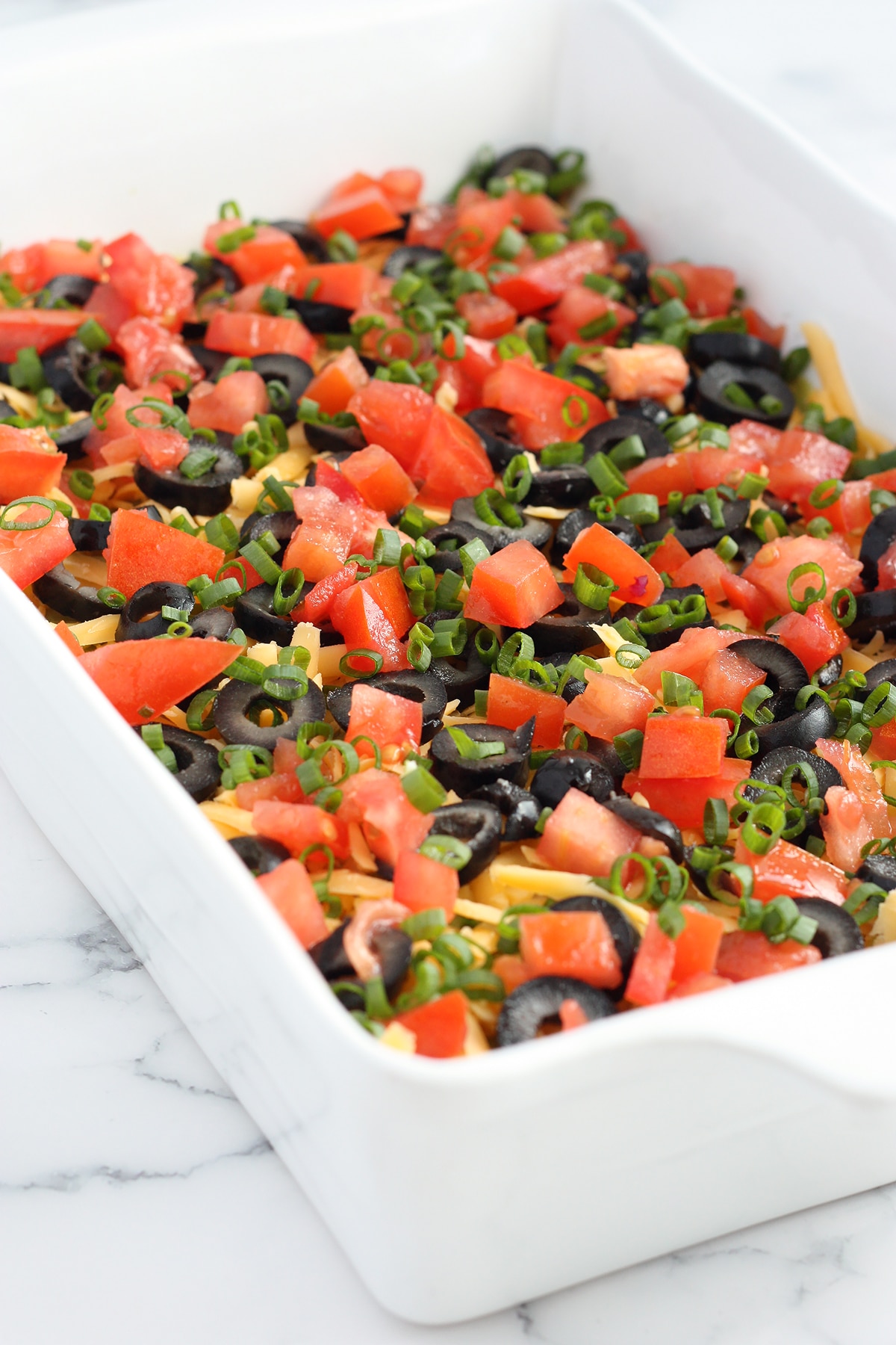 7 layer casserole with tomatoes, olives and green onions