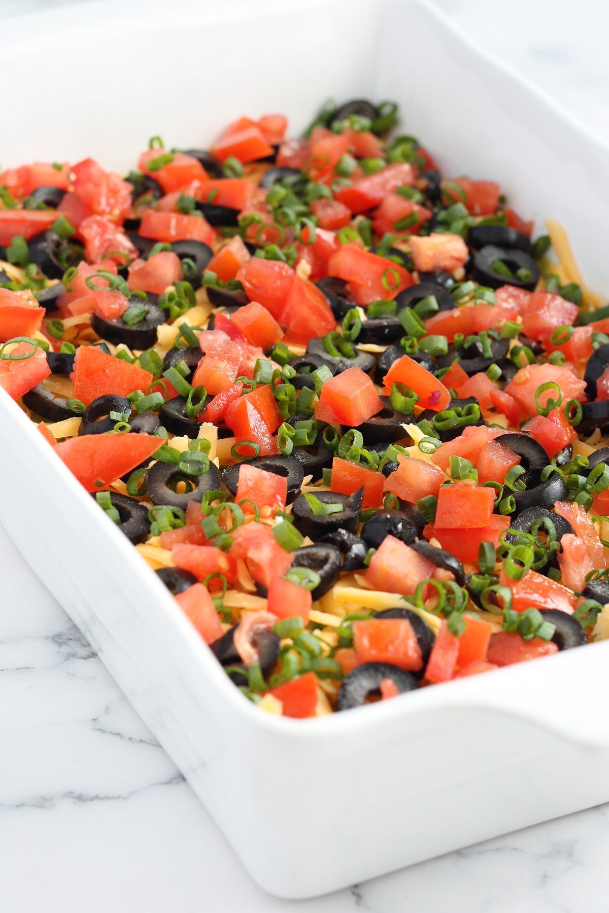 7-layer casserole with tomatoes, olives and spring onions