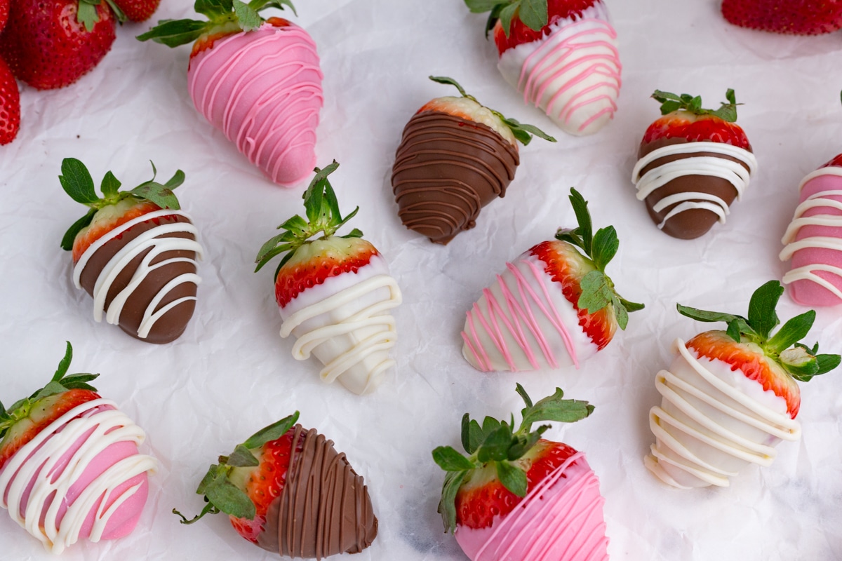 pink, white and black chocolate strawberries scattered on the counter
