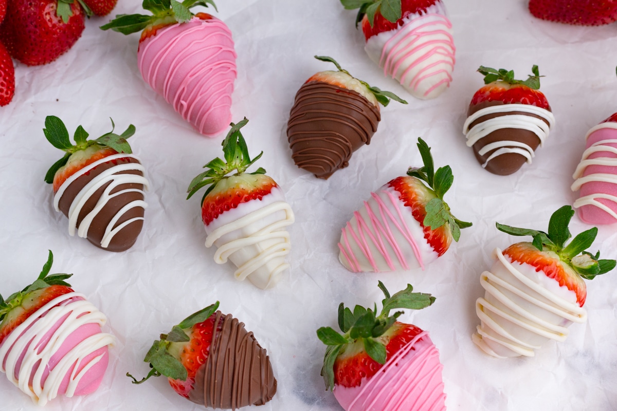 pink, white and dark chocolate strawberries scattered on the counter