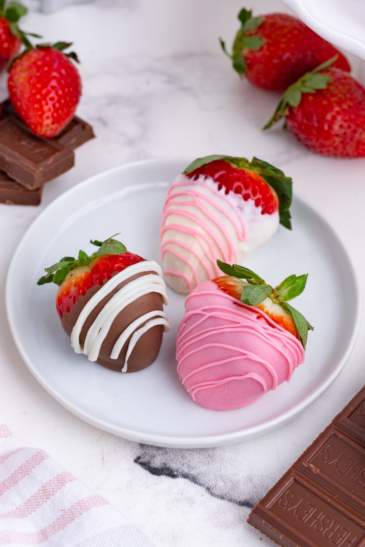 Three strawberries dipped in chocolate on a plate