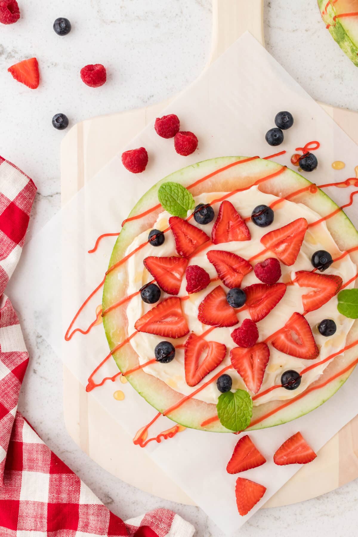 A watermelon pizza on a wooden board and topped with fresh berries.